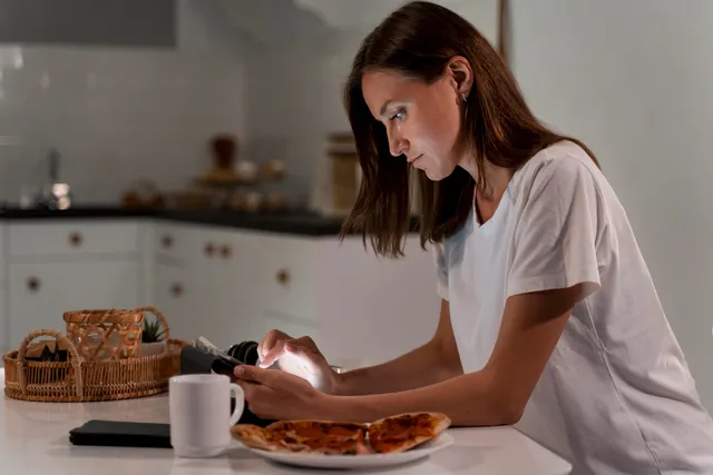 Junge Frau am Frühstückstisch stützt das Kinn auf die Hand