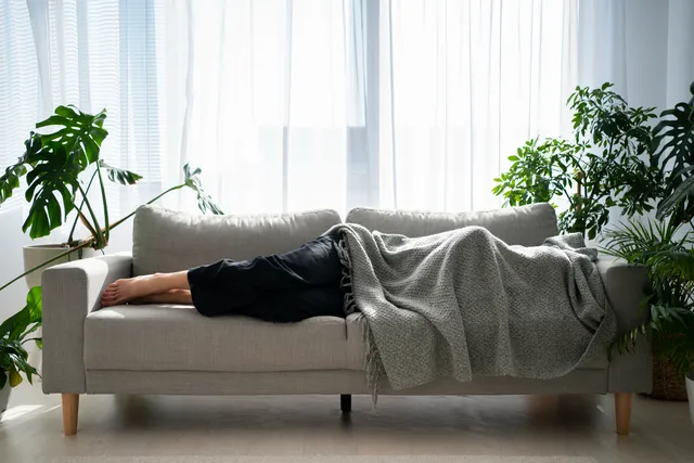 Frau sitzt entspannt auf einem Sofa und liest im Abendlicht